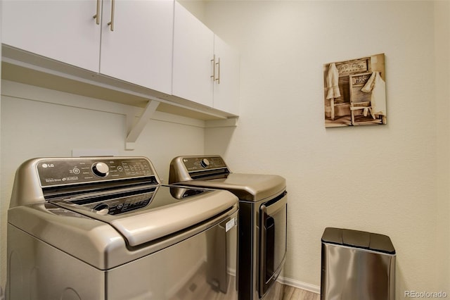 laundry room with washing machine and dryer, cabinet space, and baseboards