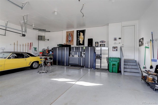 garage featuring a garage door opener and stainless steel fridge with ice dispenser