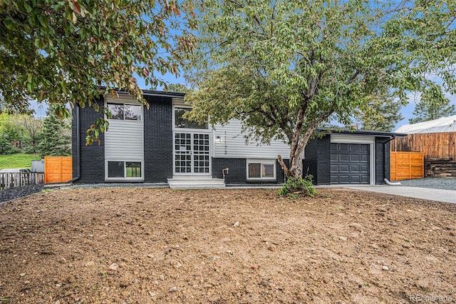 11172 W Exposition Dr, Denver, CO 80226 - view of front of home with brick siding, an attached garage, concrete driveway, and fence