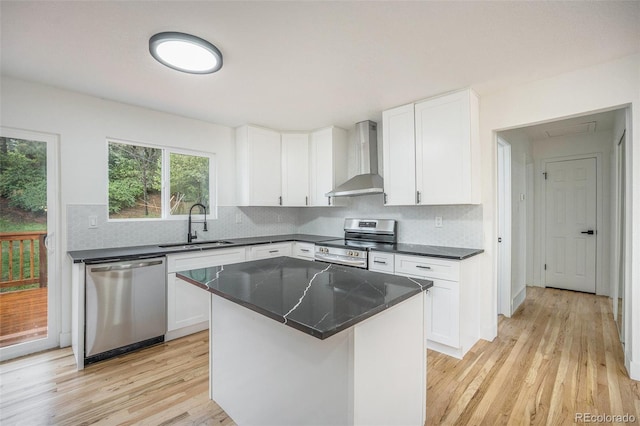 11172 W Exposition Dr, Denver, CO 80226 - kitchen featuring appliances with stainless steel finishes, wall chimney range hood, a sink, light wood finished floors, and backsplash