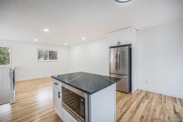 11172 W Exposition Dr, Denver, CO 80226 - kitchen with stainless steel appliances, light wood finished floors, white cabinetry, baseboards, and a center island