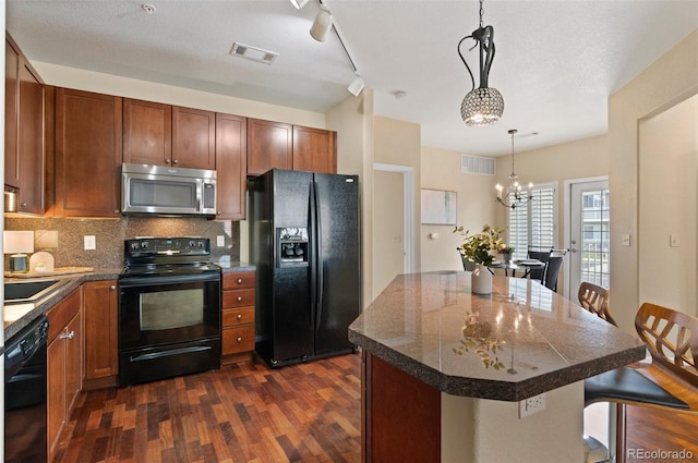 2662 S Cathay Way Unit 112, Aurora, CO 80013 - kitchen with black appliances, dark wood-style floors, a breakfast bar area, backsplash, and decorative light fixtures