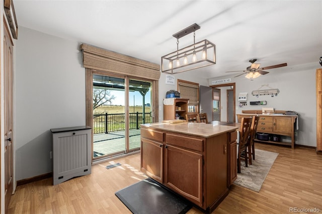 35055 E Mississippi Ave, Watkins, CO 80137 - kitchen with brown cabinetry, light wood finished floors, ceiling fan, and visible vents