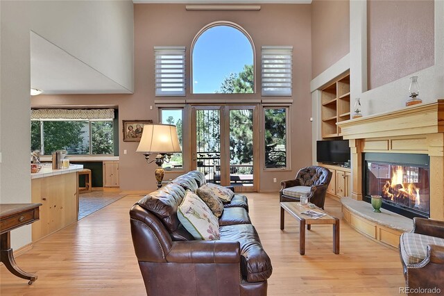 living room with light wood-type flooring and a towering ceiling