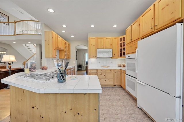 kitchen featuring tile countertops, white appliances, decorative backsplash, and light brown cabinetry