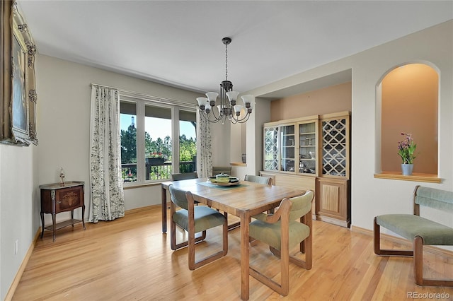 dining area with light hardwood / wood-style flooring and a notable chandelier