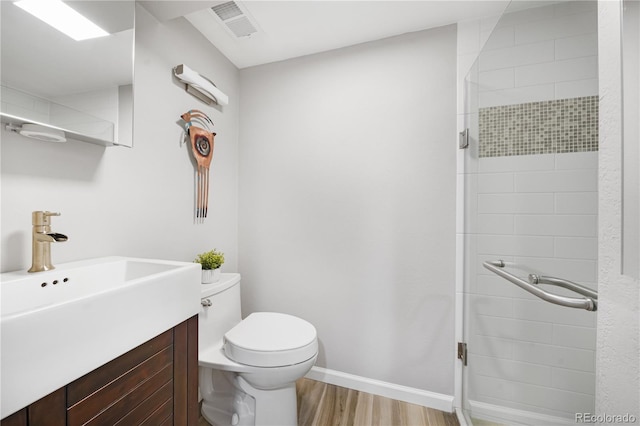 bathroom with toilet, wood finished floors, a shower stall, and vanity