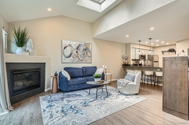 5150 Buckingham Rd, Boulder, CO 80301 - living area featuring a skylight, wood finished floors, a glass covered fireplace, recessed lighting, and lofted ceiling