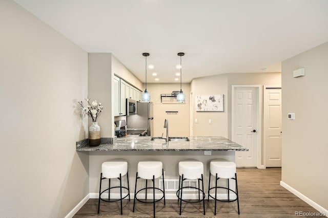5150 Buckingham Rd, Boulder, CO 80301 - kitchen with stainless steel appliances, a peninsula, a breakfast bar area, light stone countertops, and wood finished floors