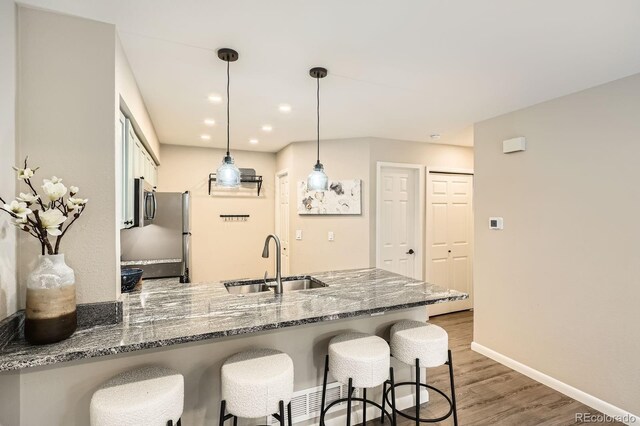 5150 Buckingham Rd, Boulder, CO 80301 - kitchen with a peninsula, wood finished floors, dark stone countertops, a breakfast bar area, and white cabinets