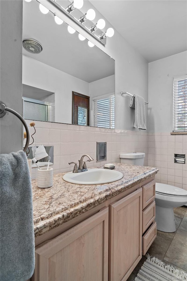 bathroom with tile walls, vanity, and toilet