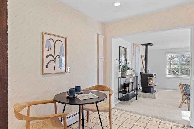 sitting room with light colored carpet, baseboard heating, and a wood stove