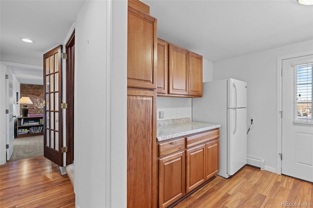 kitchen with a baseboard radiator, white fridge, and light wood-type flooring