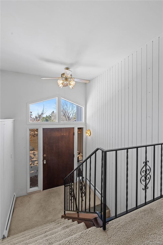 entryway featuring vaulted ceiling, a baseboard heating unit, light carpet, and ceiling fan