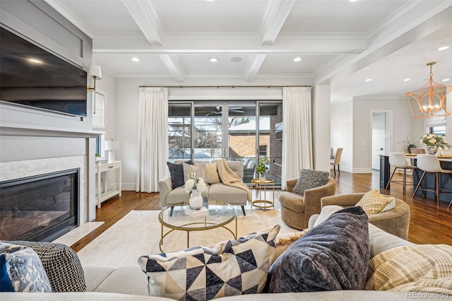 living room with beamed ceiling, hardwood / wood-style flooring, coffered ceiling, crown molding, and an inviting chandelier