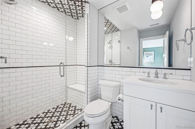 bathroom featuring walk in shower, vanity, toilet, and tile walls