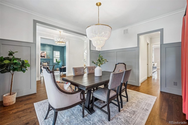 dining space featuring crown molding, dark wood-type flooring, and a chandelier