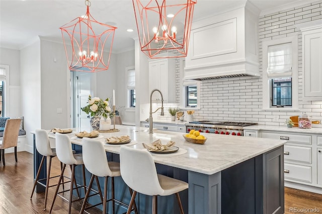 kitchen with white cabinetry, crown molding, a center island with sink, and backsplash