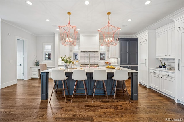 kitchen featuring white cabinetry, an island with sink, and decorative light fixtures