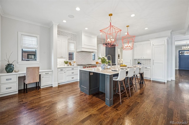 kitchen with white cabinetry, tasteful backsplash, an island with sink, and custom exhaust hood