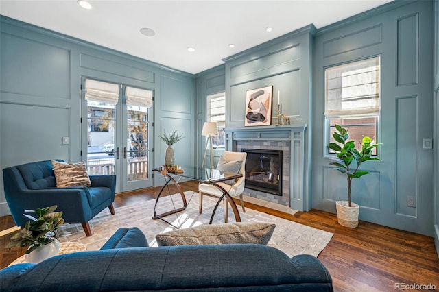 living room featuring a decorative wall, french doors, wood finished floors, and a fireplace with flush hearth