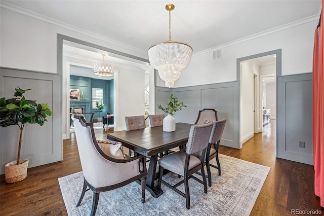 dining room featuring dark wood-type flooring, a notable chandelier, ornamental molding, and visible vents