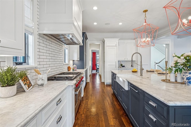 kitchen featuring blue cabinetry, white cabinets, a sink, range with two ovens, and backsplash