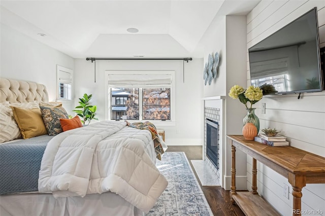 bedroom with a fireplace with flush hearth, dark wood-type flooring, multiple windows, and baseboards
