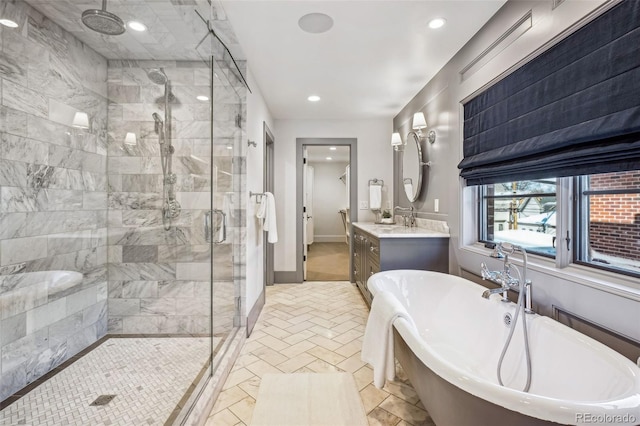 bathroom with a stall shower, vanity, a freestanding bath, and recessed lighting