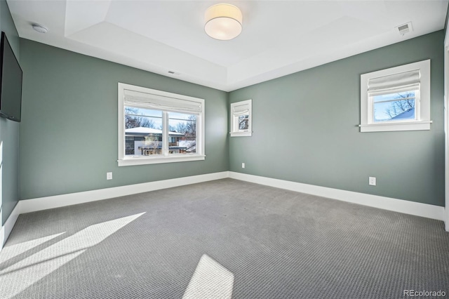 unfurnished room with a raised ceiling, baseboards, visible vents, and carpet floors