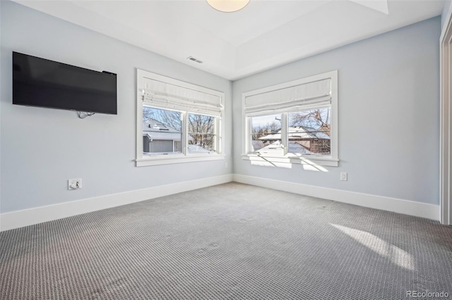spare room with a healthy amount of sunlight, carpet flooring, baseboards, and visible vents