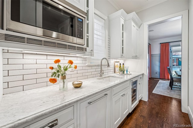 kitchen with crown molding, dark wood finished floors, white cabinetry, stainless steel microwave, and a sink