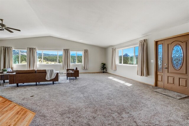 interior space with ceiling fan, carpet floors, a healthy amount of sunlight, and vaulted ceiling