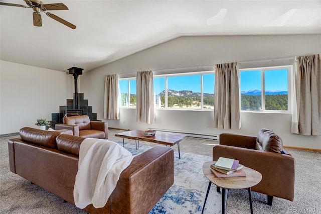 carpeted living room with a mountain view, a wood stove, a baseboard heating unit, vaulted ceiling, and ceiling fan