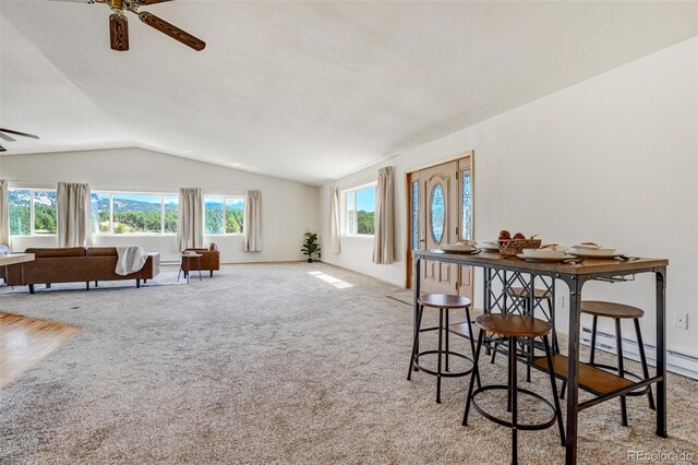 carpeted dining area featuring a baseboard radiator, vaulted ceiling, and ceiling fan