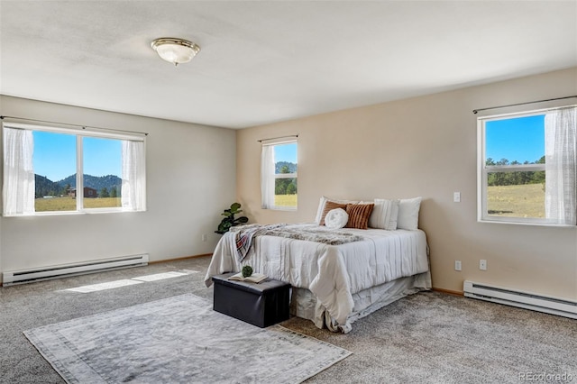 carpeted bedroom featuring a mountain view, multiple windows, and a baseboard heating unit