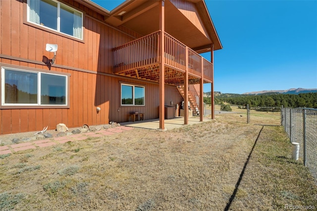 back of property featuring a deck with mountain view and a patio