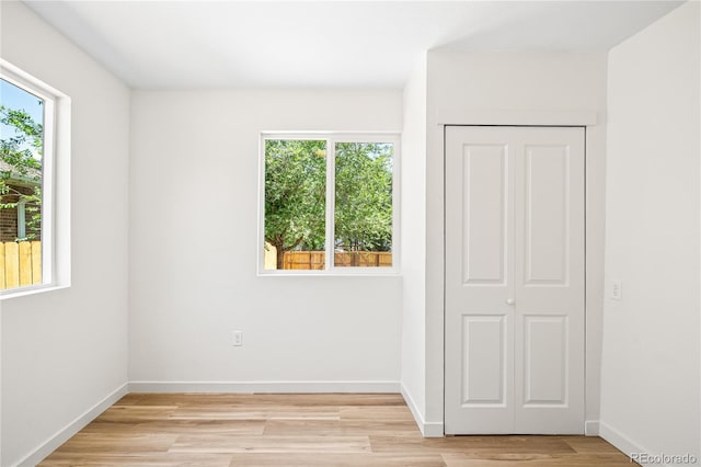 261 Knox Ct, Denver, CO 80219 - unfurnished bedroom featuring multiple windows, light wood-style floors, and a closet