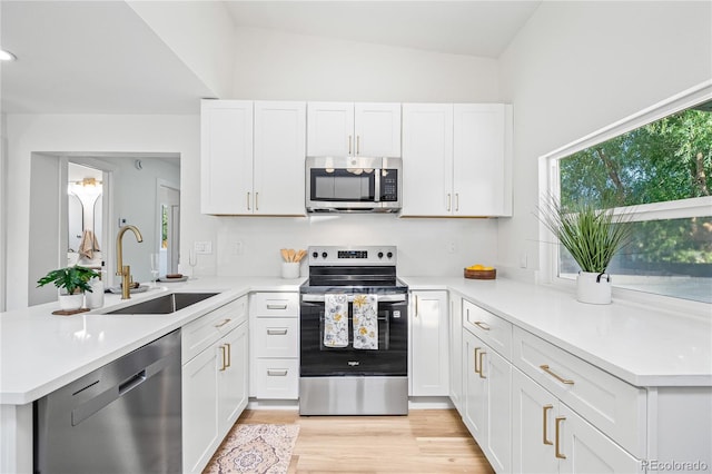 261 Knox Ct, Denver, CO 80219 - kitchen featuring appliances with stainless steel finishes, a peninsula, light countertops, white cabinets, and light wood finished floors