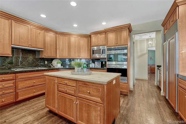 16150 Cliffrock Ct, Colorado Springs, CO 80921 - kitchen with appliances with stainless steel finishes, wood finished floors, under cabinet range hood, backsplash, and recessed lighting