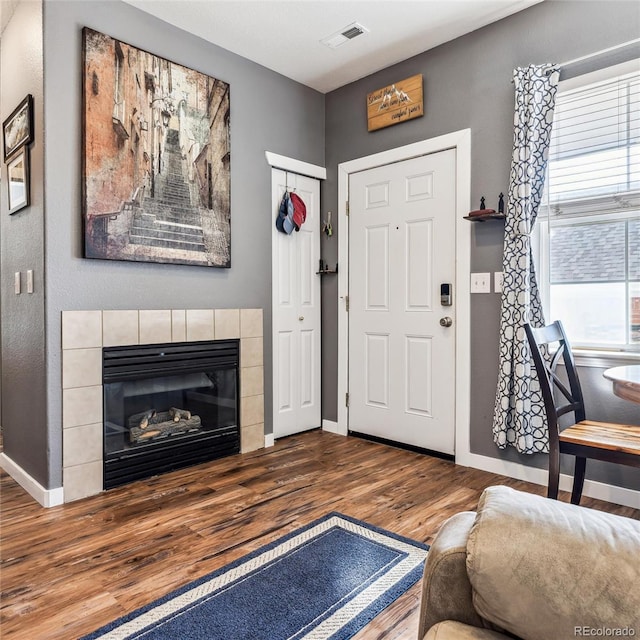 foyer entrance with a tiled fireplace and hardwood / wood-style flooring