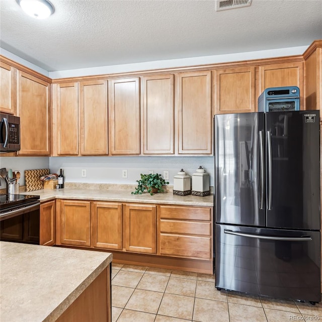 kitchen featuring electric range oven, light tile patterned floors, a textured ceiling, and refrigerator