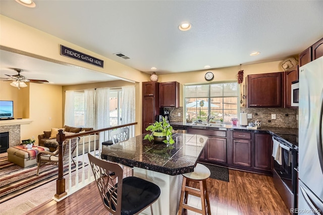 2115 Coach House Loop, Castle Rock, CO 80109 - kitchen with stainless steel appliances, tile counters, a breakfast bar area, dark wood-style flooring, and recessed lighting