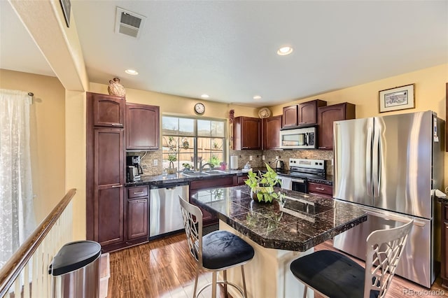 2115 Coach House Loop, Castle Rock, CO 80109 - kitchen with appliances with stainless steel finishes, tile countertops, a kitchen bar, a sink, and backsplash