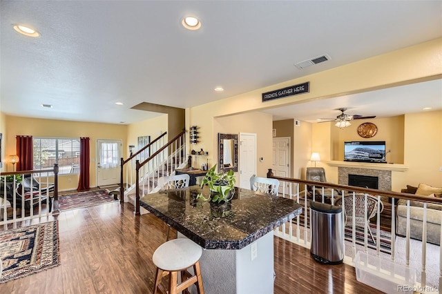 2115 Coach House Loop, Castle Rock, CO 80109 - kitchen with open floor plan, dark wood-style floors, a fireplace, a breakfast bar, and a center island