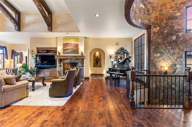 living room featuring a towering ceiling, hardwood / wood-style floors, a large fireplace, and beam ceiling