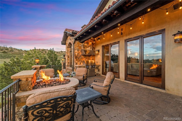 patio terrace at dusk featuring a grill and an outdoor fire pit