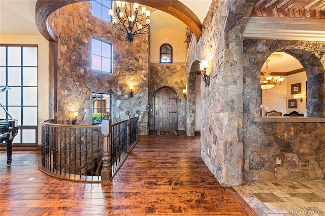 foyer entrance featuring a notable chandelier, dark hardwood / wood-style floors, and a towering ceiling