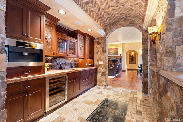 kitchen with light hardwood / wood-style floors, brick ceiling, tasteful backsplash, wine cooler, and stainless steel oven