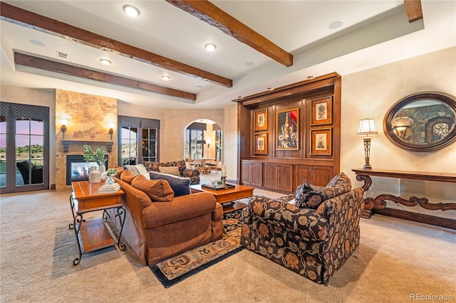 living room with beamed ceiling, a large fireplace, and carpet flooring